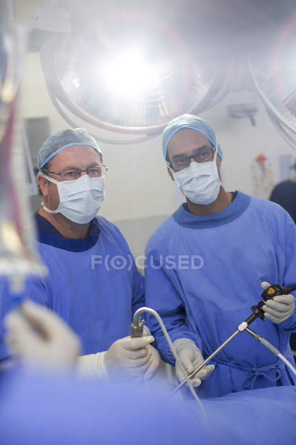 Deux chirurgiens masculins portant une chirurgie laparoscopique dans le bloc opératoire — Photo de stock