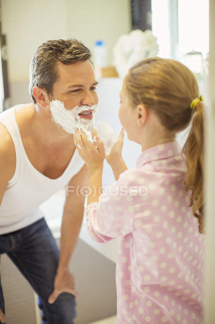 Fille frotter crème à raser sur le visage du père — Photo de stock