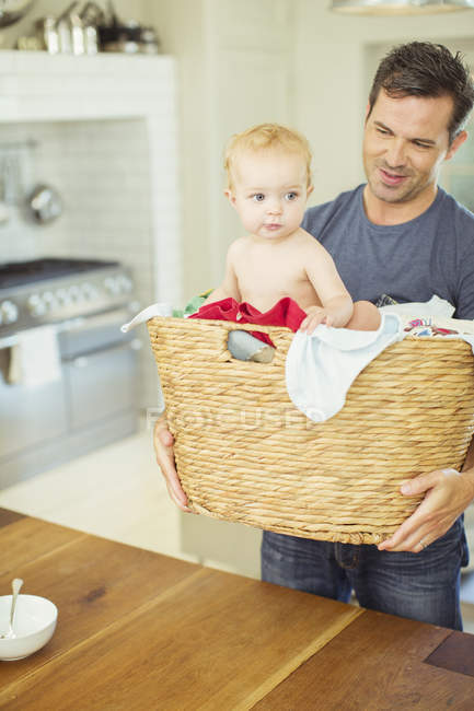 Padre llevando al bebé en la cesta de lavandería - foto de stock