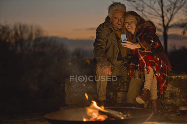 Пара використовує мобільний телефон восени безтурботний — стокове фото