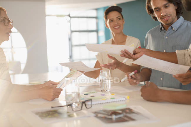 Creative business people brainstorming, passing paperwork in conference room meeting — Stock Photo