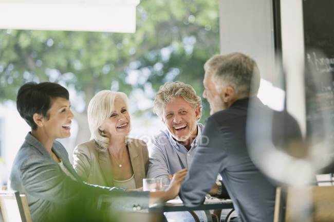 Smiling couples talking and dining at restaurant table — Stock Photo