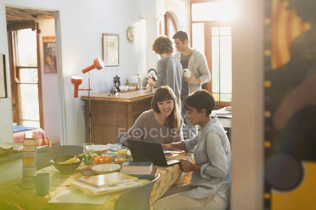 Молодые женщины учатся за компьютером за кухонным столом — стоковое фото