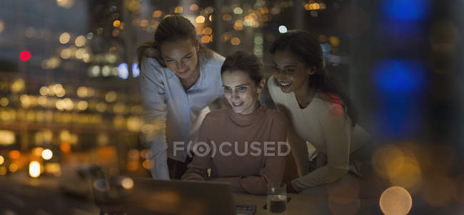 Деловые женщины, работающие допоздна за ноутбуком в офисе ночью — стоковое фото