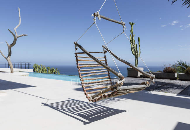 Hängender Holzstuhl auf luxuriöser Terrasse mit Blick auf das Meer — Stockfoto