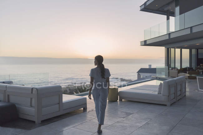 Жінка ходить на розкішному домашньому вітрині зовнішнього патіо на заході сонця — стокове фото