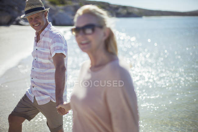 Пара, держащаяся за руки на пляже — стоковое фото