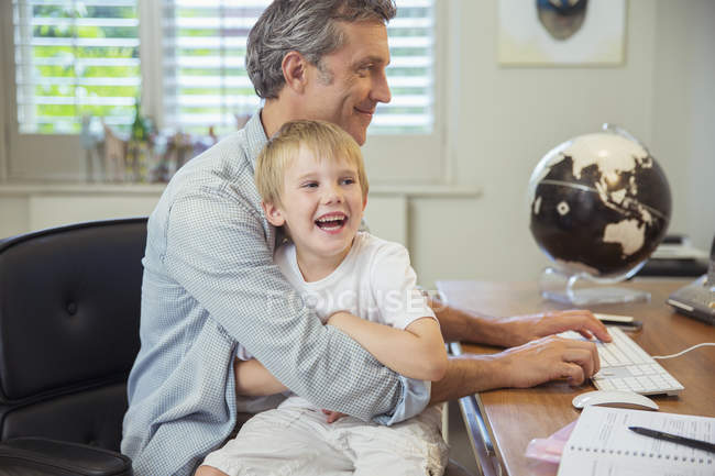 Father holding son and using computer — Stock Photo