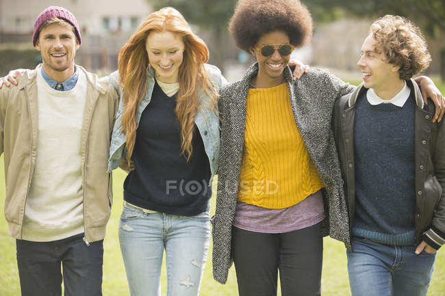 Felici giovani amici che camminano insieme nel parco — Foto stock