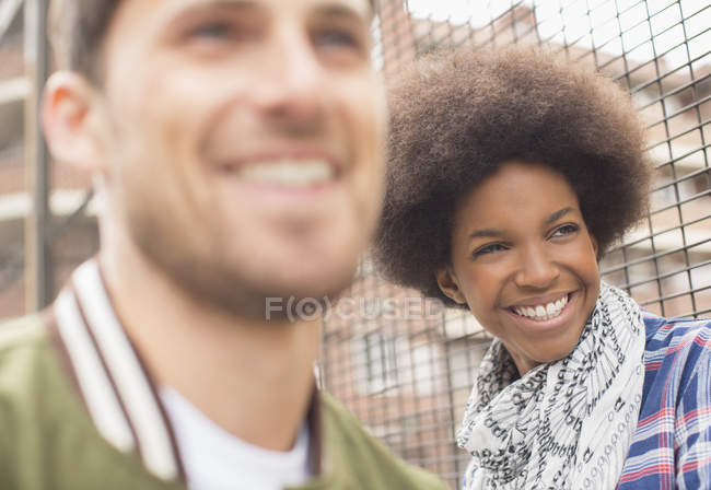 Feliz joven hombre y mujer sonriendo cerca de valla - foto de stock