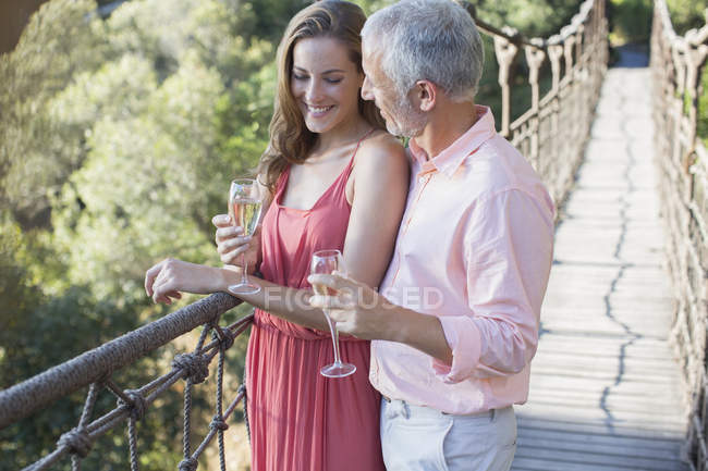 Casal brindar uns aos outros na ponte de corda de madeira — Fotografia de Stock