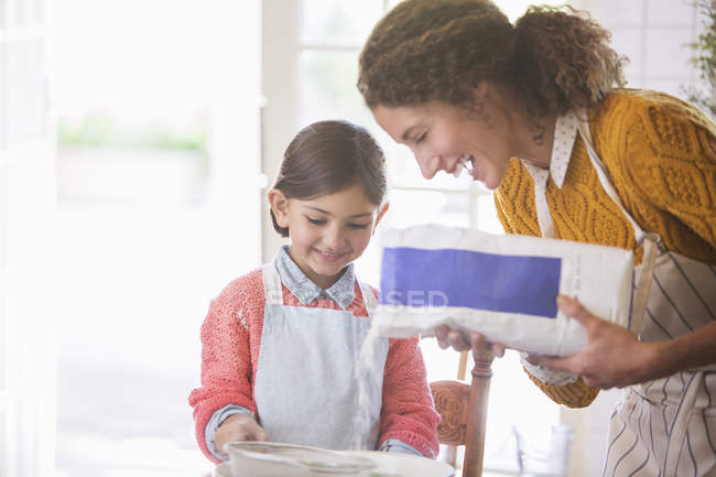 Happy modern mother and daughter baking together — Stock Photo