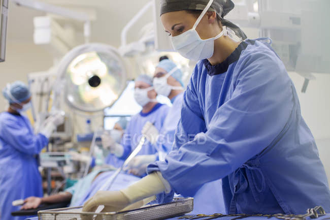 Enfermeira vestindo esfoliação preparando instrumentos médicos em sala de operações — Fotografia de Stock
