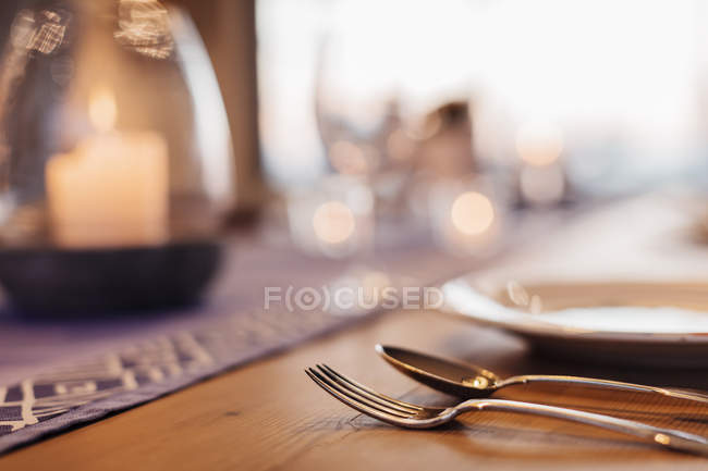 Close up illuminated candle and placesetting on dining table — Stock Photo