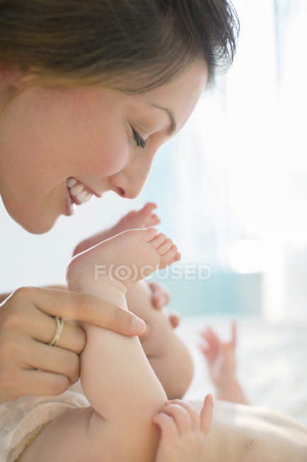Mère embrasser les pieds de bébé fille — Photo de stock
