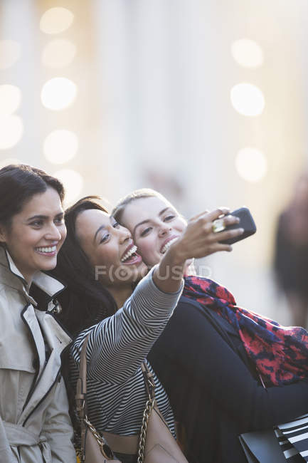 Amici che parlano foto con il cellulare insieme sulla strada della città — Foto stock