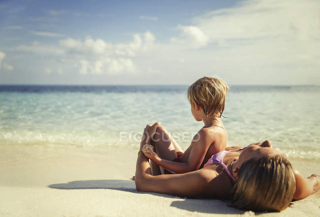 Mãe e filho deitado e relaxante na praia tropical — Fotografia de Stock