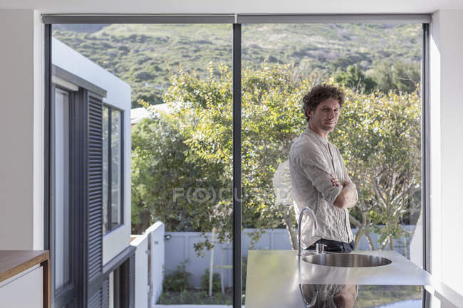Retrato homem confiante em casa moderna ensolarada vitrine cozinha interior — Fotografia de Stock