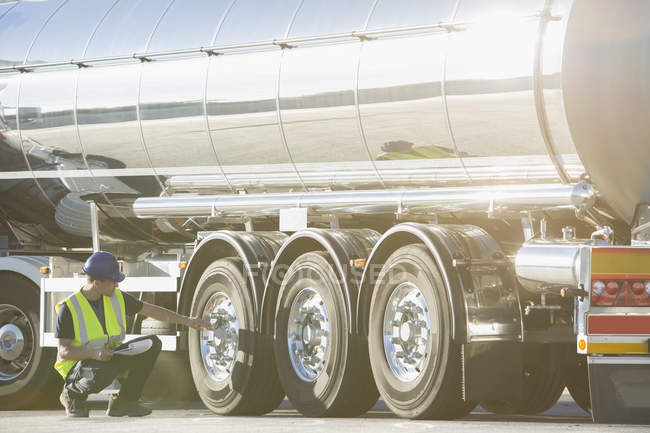 Worker checking tire on stainless steel milk tanker — Stock Photo