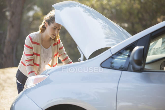 Femme vérifiant moteur de voiture au bord de la route — Photo de stock