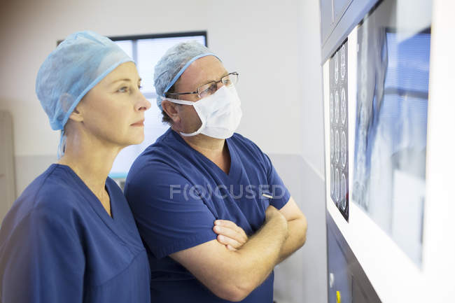 Dos doctores discutiendo la radiografía del paciente y la resonancia magnética antes de la cirugía - foto de stock