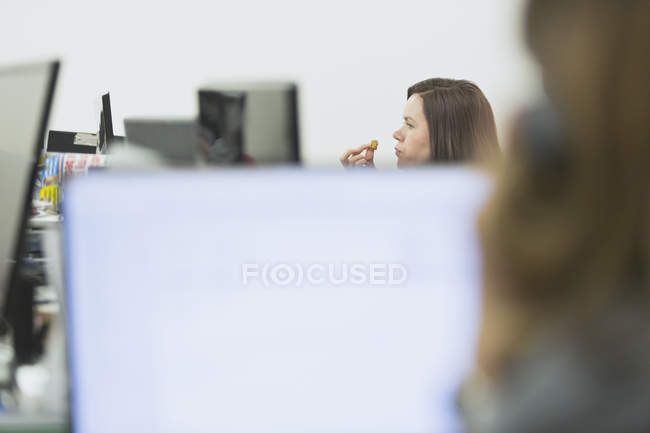 Imprenditrice che mangia e lavora alla scrivania in ufficio — Foto stock