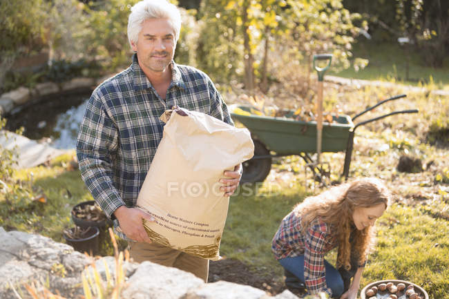 Portrait couple gardening holding potting soil in autumn garden — Stock Photo