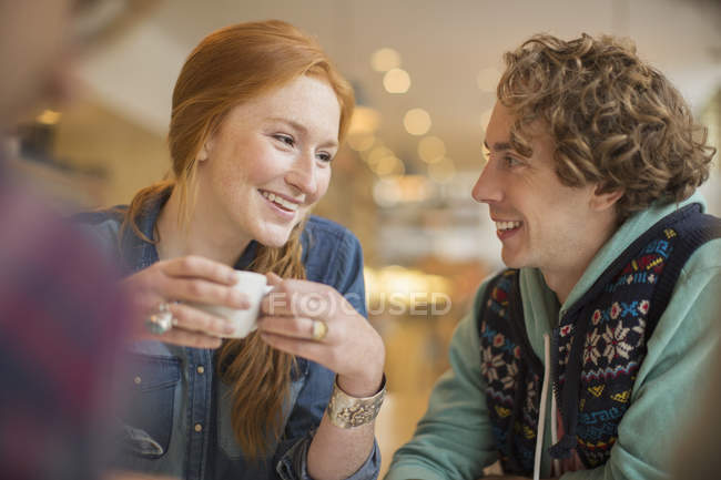 Feliz joven pareja bebiendo café en la cafetería - foto de stock
