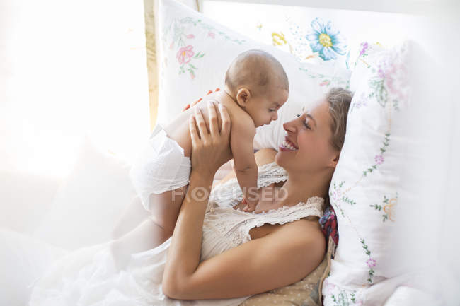 Madre holding bambino ragazzo su letto — Foto stock