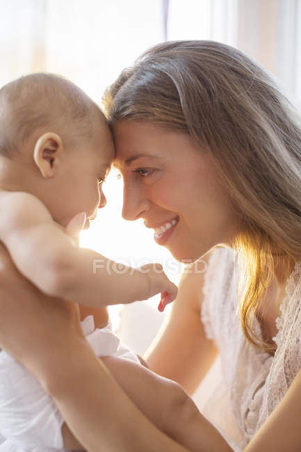 Madre tocando frentes con bebé niño - foto de stock