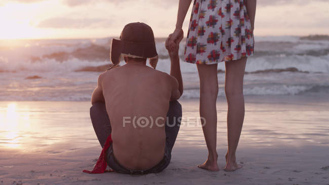 Молода пара тримає руки на пляжі на заході сонця — стокове фото