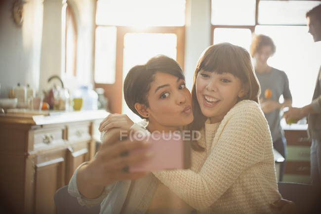 Juguetones jóvenes amigos tomando selfie con cámara de teléfono haciendo una cara - foto de stock