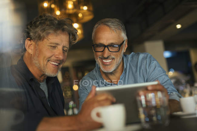 Men using digital tablet at restaurant table — Stock Photo