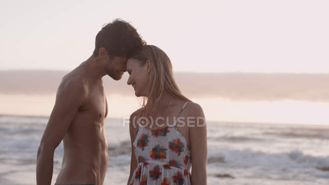 Cariñosa pareja joven en la playa - foto de stock