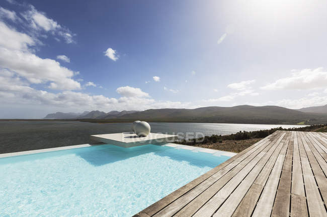 Солнечный спокойный современный бассейн с видом на океан — стоковое фото