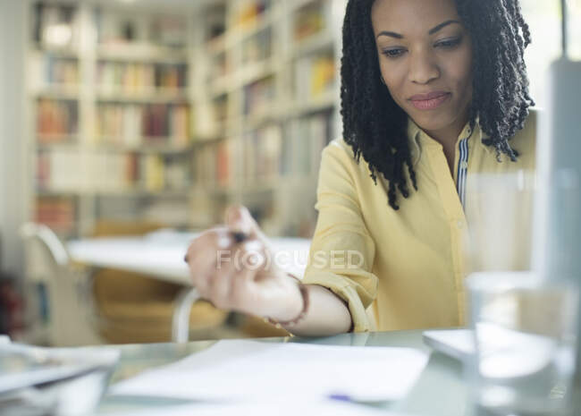 Businesswoman with paperwork at laptop — Stock Photo