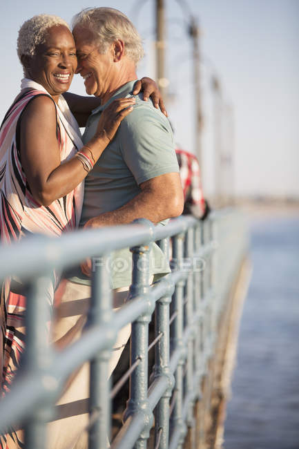 Seniorenpaar umarmt sich auf Seebrücke — Stockfoto