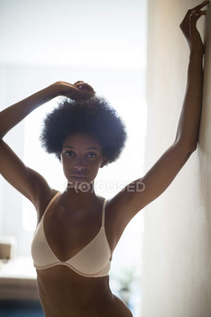 Woman wearing bra in corridor posing with raised arms — Stock Photo