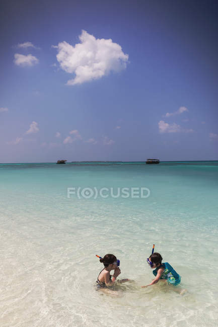 Niño y niña hermano y hermana haciendo snorkel en el soleado océano tropical azul - foto de stock