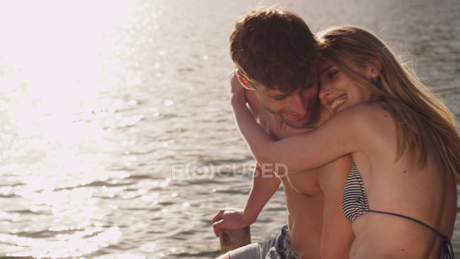 Cariñosa pareja joven abrazándose en el lago - foto de stock