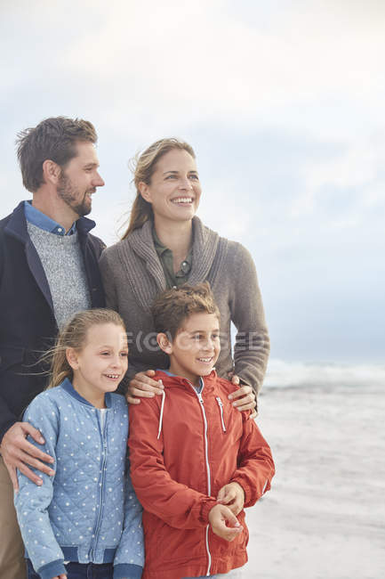 Feliz familia sonriente en la playa de invierno - foto de stock