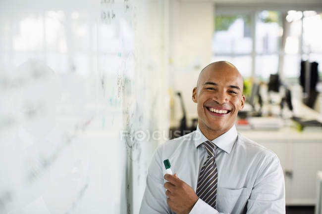 Homme d'affaires souriant au tableau blanc dans le bureau — Photo de stock