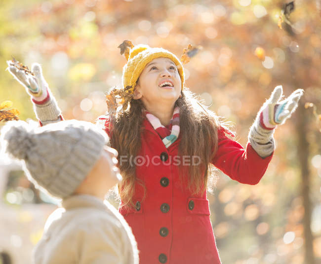 Chica lanzando hojas de otoño en el parque - foto de stock