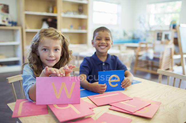 Estudantes segurando cartas em sala de aula — Fotografia de Stock