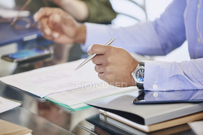 Abgeschnittenes Bild eines Geschäftsmannes, der bei einer Besprechung den Stift über den Papierkram hält — Stockfoto