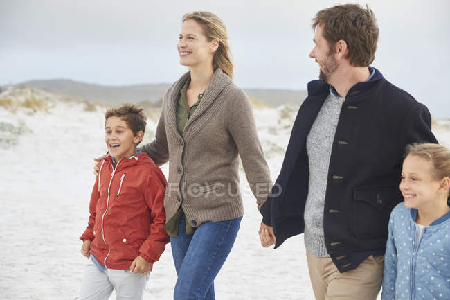 Family holding hands walking on winter beach — Stock Photo