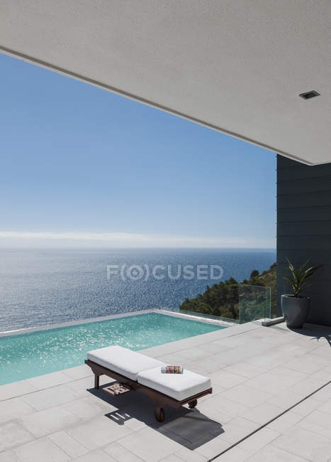Cadeira de salão por piscina infinita com vista para o mar — Fotografia de Stock