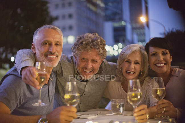 Retrato sorrindo casais bebendo vinho branco no café da calçada — Fotografia de Stock