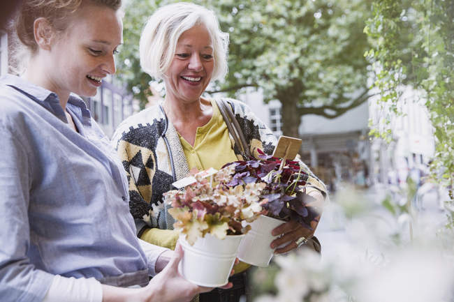 Florist showing potted plants to female shopper at storefront — Stock Photo