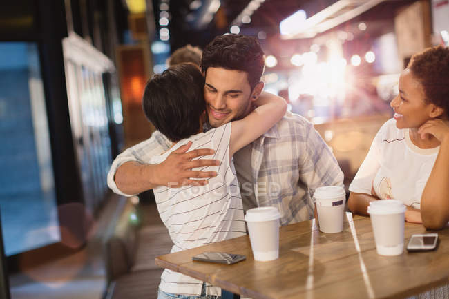 Young couple hugging, drinking coffee in cafe — Stock Photo